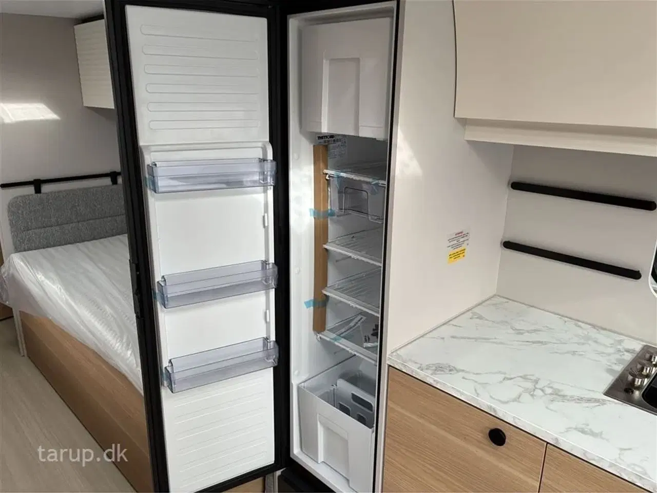 Billede 13 - 2026 - Adria Adora 663 UT Alde   ALDE centralvarme, elektrisk gulvvarme, frontkøkken, rundsiddegruppe, SmartBox gaskasse opbevaring, stort køleskab, enkeltsenge