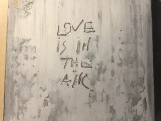 Maleri i grå med teksten "Love is in the air"