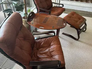 To læderlænestole, en fodskammel og et træbord