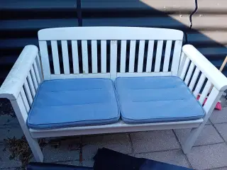 Hvid havebænk med lyseblå hynder.