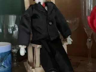 Chaplin porcelændukke i gyngestol af tøjklemmer.