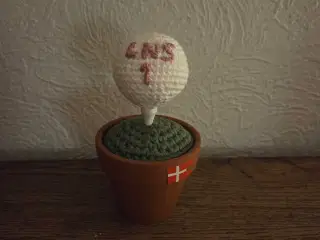 Hæklet golfbold med initialer på tee, i potte