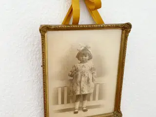 Sort/hvid foto af lille pige i guldramme, dat. 1928