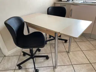Bord med to plader samt to stole på hjul