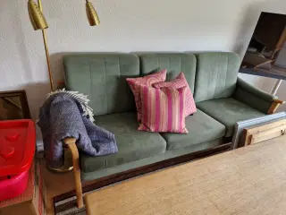 Sofa i eg med grønt betræk.