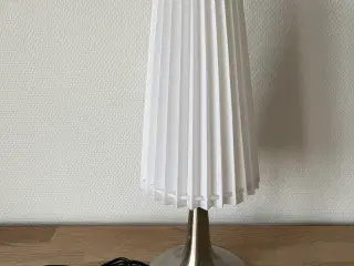 Sølvfarvet bordlampe med hvid plisseskærm