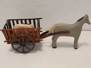 Gammel træhest der trækker metalvogn med trægris. 