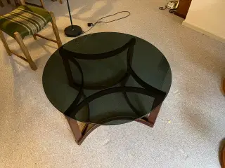 Sofabord med stel i mørkt træ og tonet glasplade.