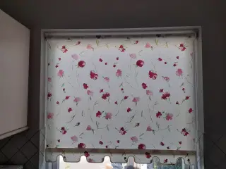 Rullegardin med blomster i røde og grønne nuancer.