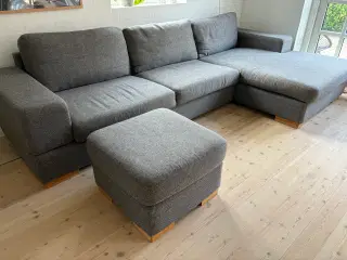 Grå sofa med chaiselong og puf