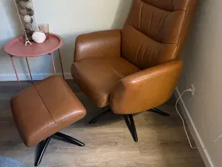 Læne/drejestol i brunt læder med fodskammel.
