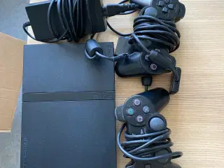 Playstation 2 med tilbehør der kan ses på billedet
